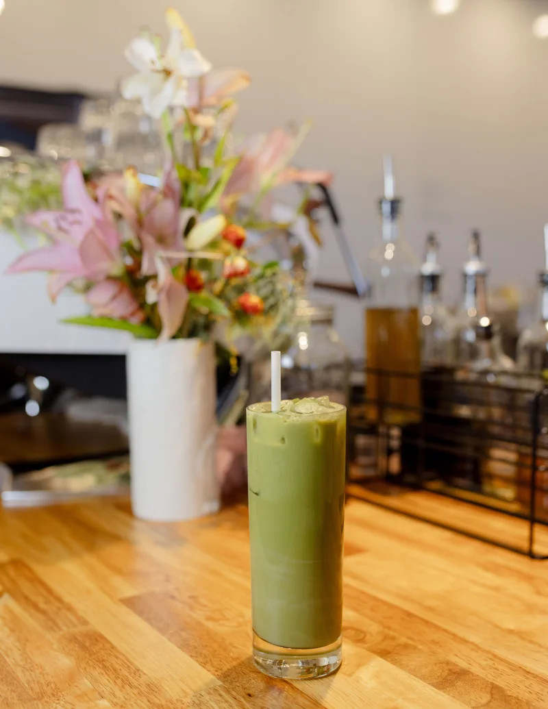 An iced matcha beside flowers on the Give & Take counter