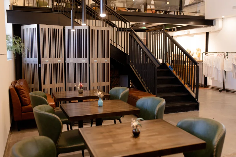 Wooden tables, green chairs, and the staircase inside Give & Take